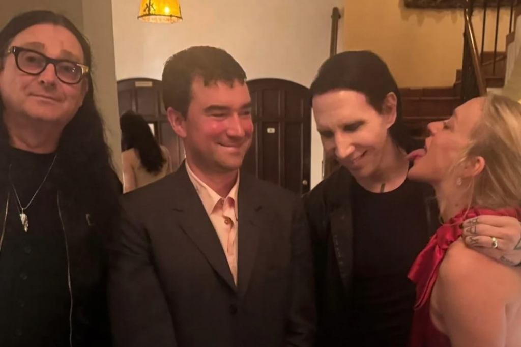 The Mosh Network - Chloë Sevigny playfully posing as if licking Marilyn Manson’s face while standing with filmmaker Jonas Åkerlund at an Emmy afterparty in September 2025.
