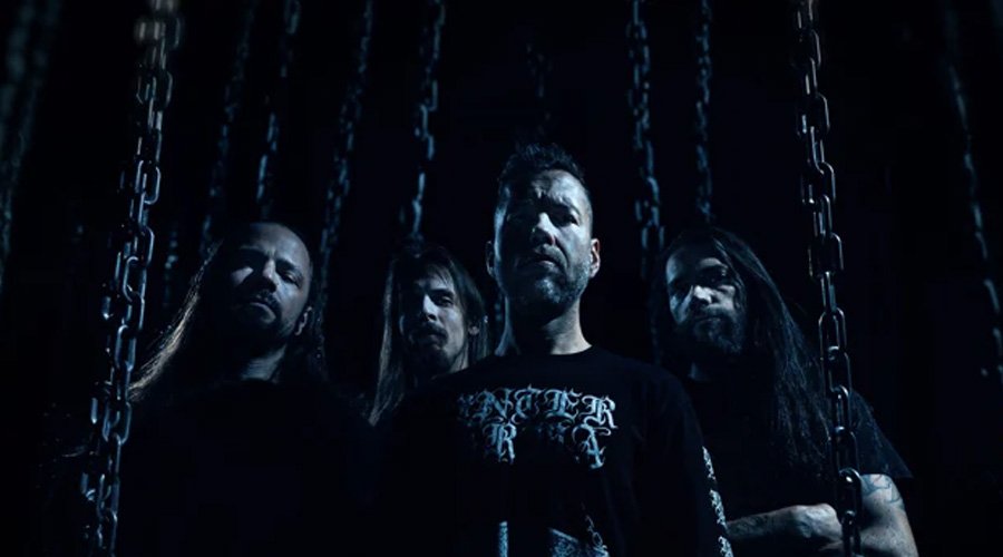 Revocation Debut “Confines Of Infinity” Music Video, Cattle Decapitation’s Travis Ryan Guests The Mosh Network - Revocation band photo with the members in a dark room with blue tinted lighting. 2025.