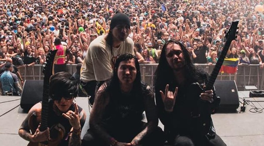 ESCAPE THE FATE Earn First-Ever Gold Record for Debut Album Escape The Fate pose on stage with guitars in front of a massive festival crowd during a daytime performance.